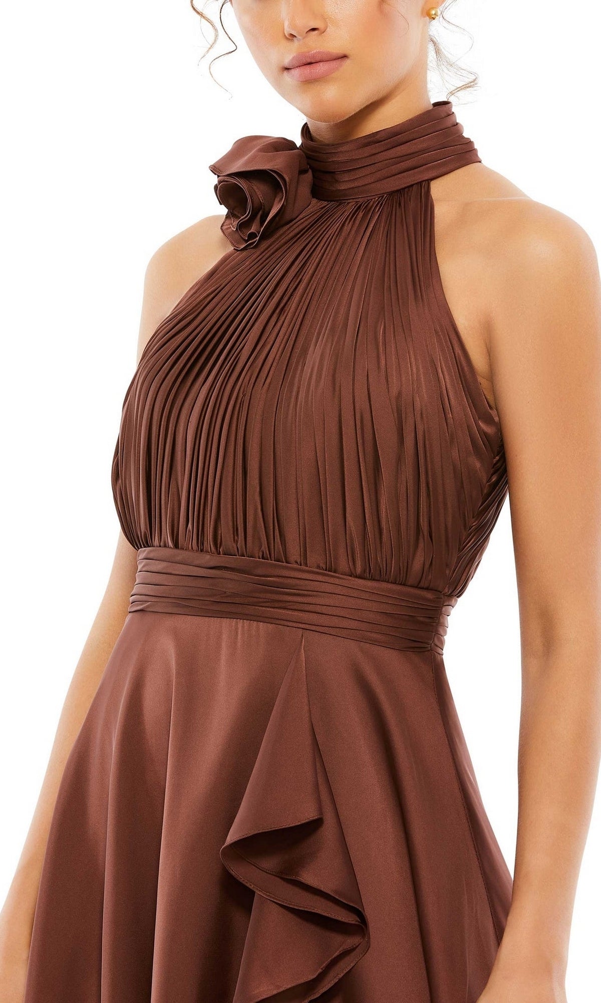 A woman wears the High-Low Wedding Guest Dress: Mac Duggal 49488, a sleeveless brown pleated dress with a high neck, fabric rose detail, and fitted waistband.